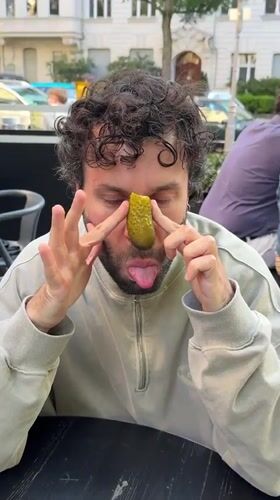 Man plays with pickle at Berlin outdoor cafe