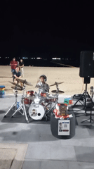 Young drummer performs beachside at night in Pattaya