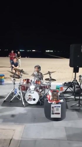 Young drummer performs beachside at night in Pattaya