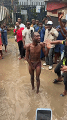 Crowd surrounds restrained person in muddy puddle, Ihiagwa, Nigeria