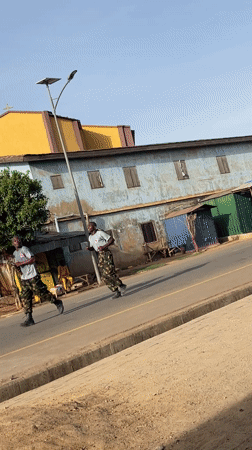 Seven men jog through urban Nigeria neighborhood