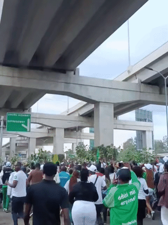 Football crowd gathers under Nairobi overpass with motorcycle riders