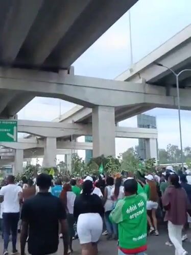 Football crowd gathers under Nairobi overpass with motorcycle riders