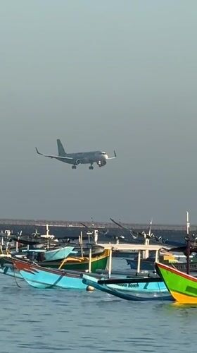 Kuta Beach at dusk: fishing boats, beachgoers, and planes overhead