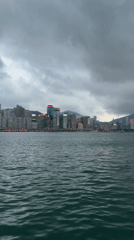 Hong Kong skyline viewed across choppy waters under cloudy skies