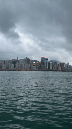 Hong Kong skyline viewed across choppy waters under cloudy skies