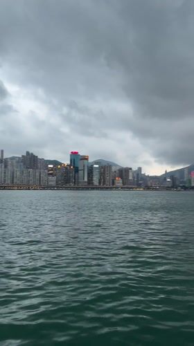 Hong Kong skyline viewed across choppy waters under cloudy skies