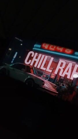 The video displays a smartphone screen showing a “Chill Rap” thumbnail, featuring a white Porsche parked outside a store with a neon sign in an Asian language. It is dark outside, and the phone is held at an angle. Music is playing from the phone's speaker.