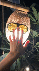 Person touches glowing woven lantern in Koh Phangan Thailand