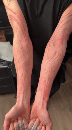 Person displays red tattoo stencils on forearms in Moscow