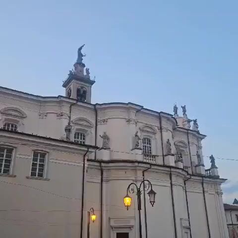 This is a video of a building with statues on it. The building appears to be a church, and the statues are of people, possibly saints. The sky is blue and there are streetlights in the foreground. The video is shot from a low angle, looking up at the building.