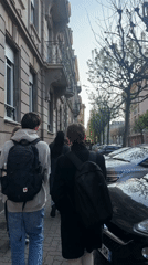 Backpack-wearing group walks Strasbourg sidewalk in afternoon sunlight