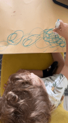 Child draws with blue marker on paper in Luxembourg