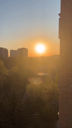 Woman films selfie session against Novosibirsk sunset cityscape