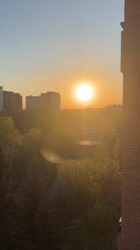 Woman films selfie session against Novosibirsk sunset cityscape