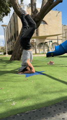 Person performs headstand at Kiryat Bialik playground on sunny morning