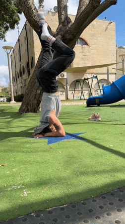 Person performs headstand at Kiryat Bialik playground on sunny morning
