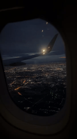 Nighttime aerial view of illuminated Bangkok captured from airplane window