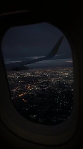 Nighttime aerial view of illuminated Bangkok captured from airplane window