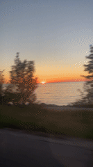 Sunrise captured over water from moving vehicle in Hayes Township