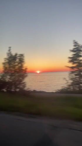 Sunrise captured over water from moving vehicle in Hayes Township