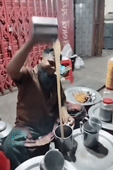 Traditional tea vendor serves customers using high-pouring technique in Dhaka