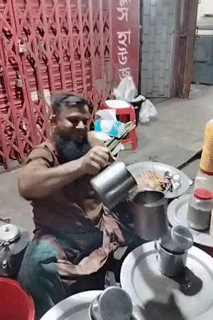 Traditional tea vendor serves customers using high-pouring technique in Dhaka