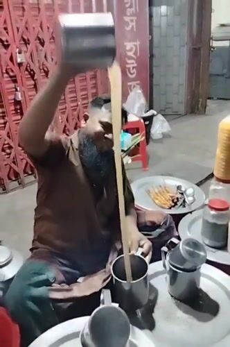 Traditional tea vendor serves customers using high-pouring technique in Dhaka