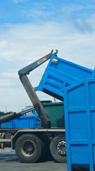 Hook loader truck lifts blue skip in sunny weather