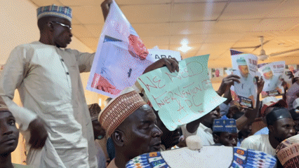 Political supporters gather with signs in Shaba, Nigeria