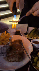 Person uses blowtorch on steak in New York restaurant