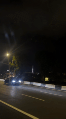 Nighttime highway scene with illuminated tower captured by witnesses