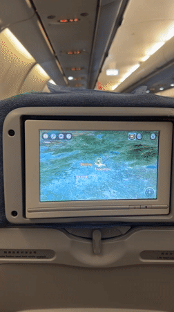 Passenger documents airplane cabin with flight maps over Beijing