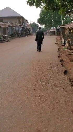 Motorcycle and foot traffic on a Bukuru market road