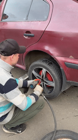 Man uses air wrench on car wheel in Moscow