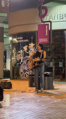 Acoustic street performance outside a glass-fronted building in Şişli