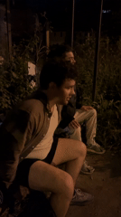 Two men sit outdoors in evening darkness in Varna
