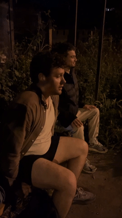 Two men sit outdoors in evening darkness in Varna