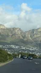 Traffic flows toward Cape Town mountains amid white buildings