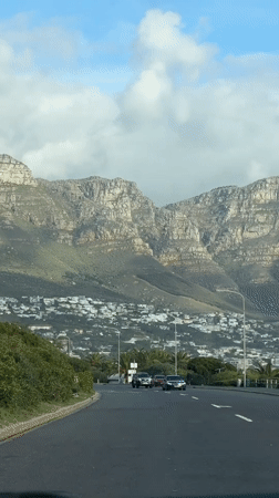 Traffic flows toward Cape Town mountains amid white buildings