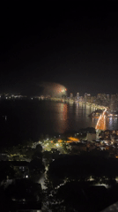 Nighttime fireworks display over coastal city from aerial views