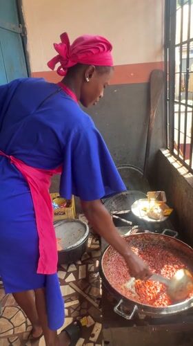 Woman cooks red sauce in kitchen, Obosi Nigeria