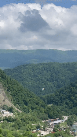 Paraglider spotted over forested mountains near Baranovka, Russia