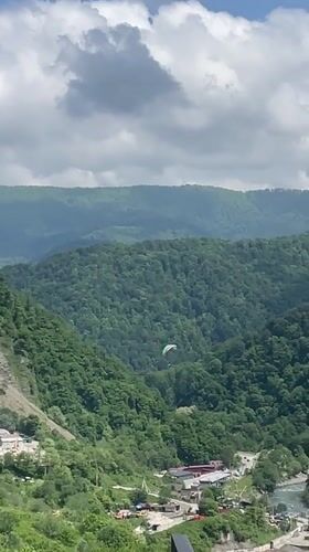 Paraglider spotted over forested mountains near Baranovka, Russia