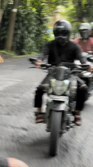 Motorcyclist in black hoodie rides through Ubud District