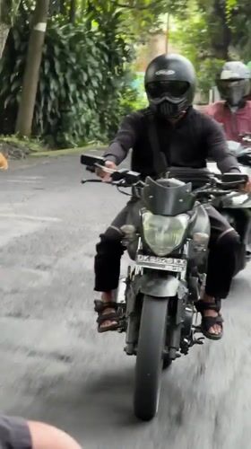 Motorcyclist in black hoodie rides through Ubud District