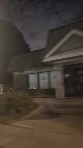 This video captures a nighttime drive through a dimly lit area in Laval, Canada. The scene is characterized by a mix of residential and possibly institutional buildings, illuminated by streetlights and interior lights.

The initial frames show a brick building with a dark roof and a lit window, partially obscured by a large tree and dense shrubbery. As the camera pans, a lamppost with decorative lights is visible, standing in a grassy area with more trees in the background.

The focal point of the video becomes a striking church with a tall steeple topped by a cross. The church is illuminated, casting a glow on the surrounding trees and a grassy lawn. In front of the church, there appear to be several illuminated statues, creating a somewhat ethereal atmosphere. The sky is dark with visible clouds, suggesting it is nighttime.

The activity is a slow drive past these locations, creating a sense of movement and observation. The lighting and the presence of the church suggest a potentially solemn or reflective mood, though the fast motion of the video can also impart a feeling of transit. No text is clearly visible in the video. The overall impression is a nocturnal journey through a quiet, possibly suburban or park-like setting in Laval, Canada, with the church serving as a prominent landmark.