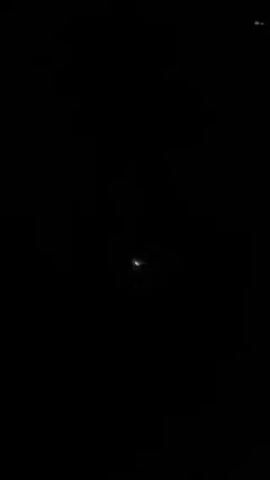 The video shows the wing of an aircraft in flight at night. The wing is lit by a red light, but the background is completely dark.