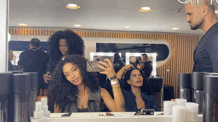 Woman uses phone in Rio salon mirror reflection