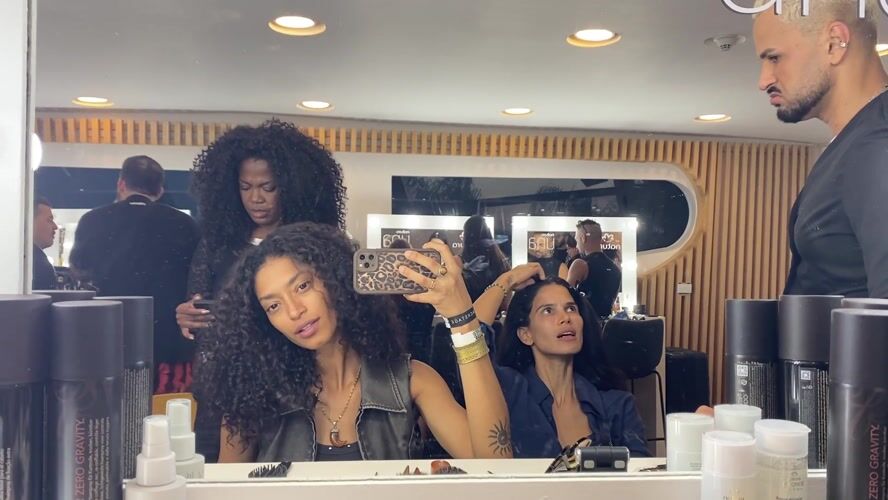 Woman uses phone in Rio salon mirror reflection